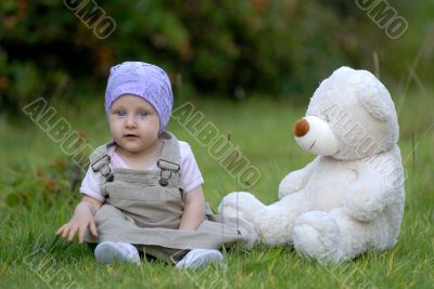 baby on the grass with a bear toy