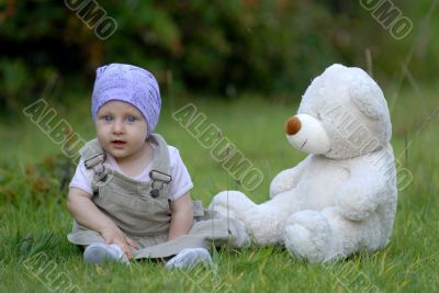 baby on the grass with a bear toy