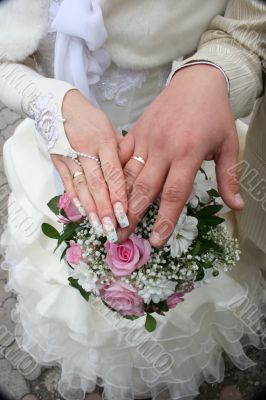 Female and male newlyweds hands with bouquete