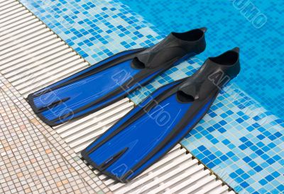Blue Flippers lay on a side of swimming pool