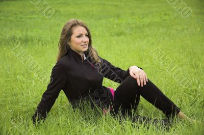 The beautiful girl sits on a green grass