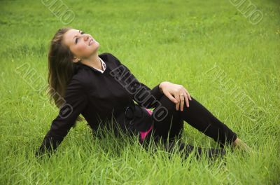 The beautiful girl sits on a green grass