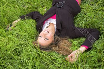 The beautiful girl sits on a green grass