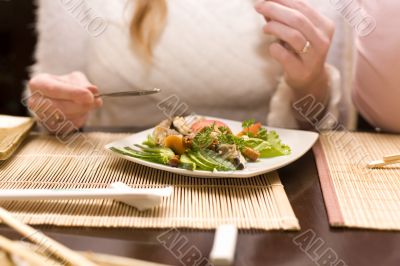 Woman eating salad in japanese restaurant