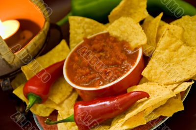closeup of candle, chips, salsa and peppers