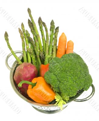 Fresh vegetables in a colander on white isolated