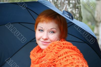 young red-haired woman in red scarf with umbrella