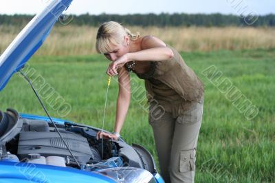 young blond woman with her broken car. The girl is sad