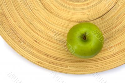 Green apple on a bamboo plate