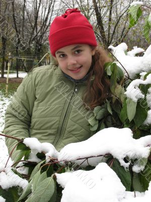 The girl in red hat near snow bush
