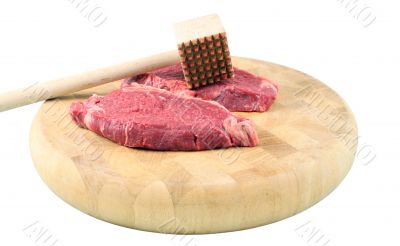 Steaks on a chopping board with Mallet