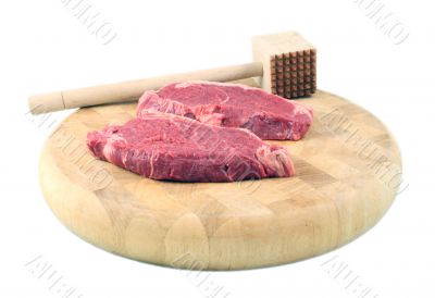 Steaks on a chopping board with Mallet