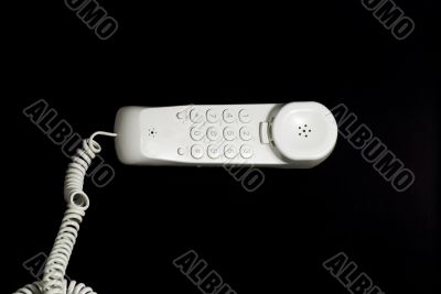 White analog phone on black background