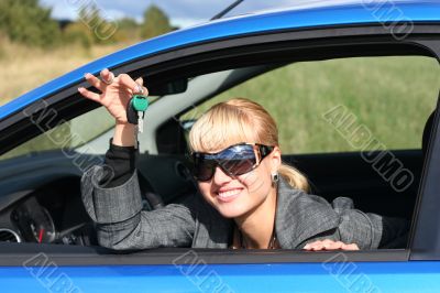 young blond woman in a blue car with key from it