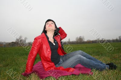 black head woman is sitting on a Plaid in park grass