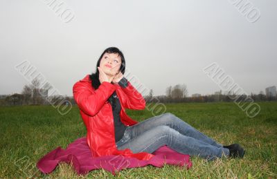 black head woman is sitting on a Plaid in park grass