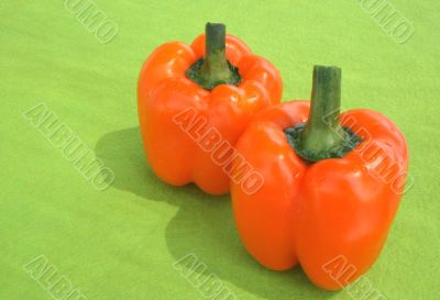 Orange peppers on green background