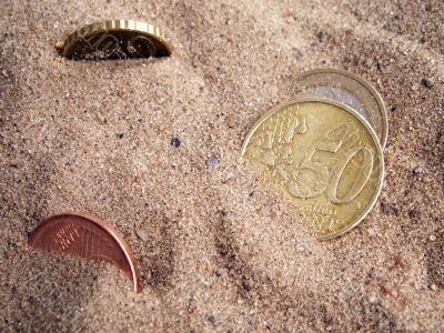 Coins on background with sand