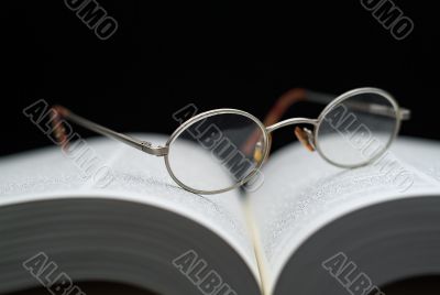 Closeup of reading glasses on large book