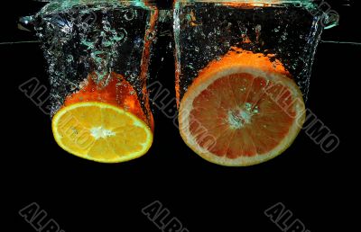 Grapefruit and ornage falling into water