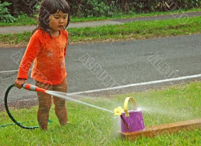 Little girl playing with water in summer day.