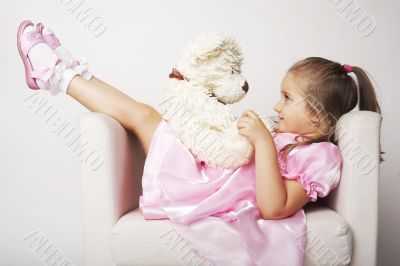 Nice young girl in pink on light background with teddy bear