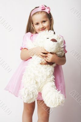 Nice young girl in pink on light background with teddy bear