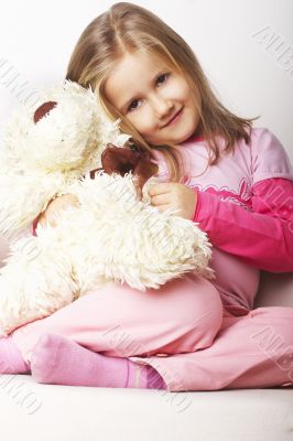 Nice young girl in pink on light background with teddy bear