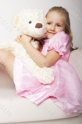 Nice young girl in pink on light background with teddy bear