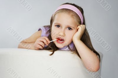 Nice young girl in pink on light background with lollipop