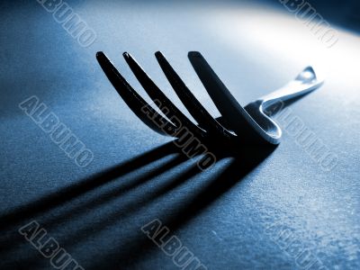 Fork tines and shadow on textured surface