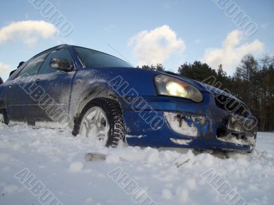blue car is slipping at snow cavered lake