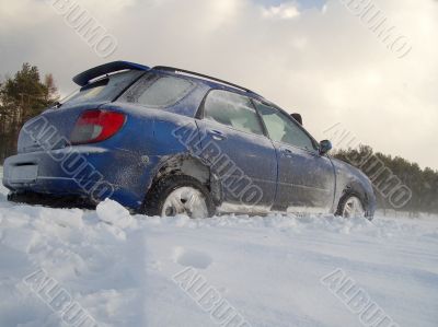 blue car is slipping at snow cavered lake