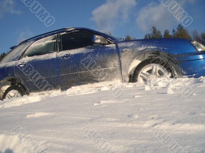 blue car is slipping at snow cavered lake