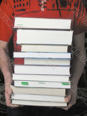 man is holding a stack of books