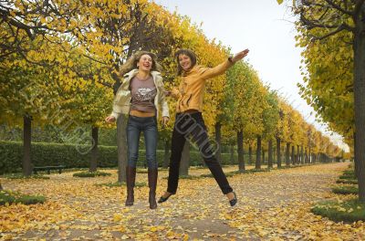 Two girls jump in autumn park