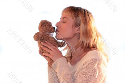 young blond woman is kissing teddy bear