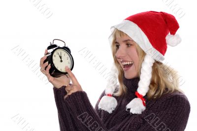 blond girl in red santa`s cap with alarm clock