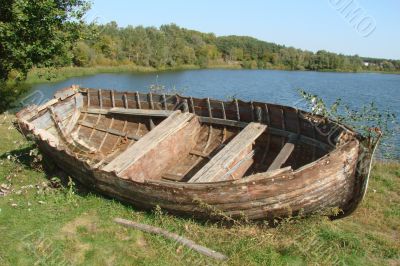 ruined vintage wooden boat on riverside
