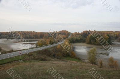 wide field with river uder cloudy deep blue sky