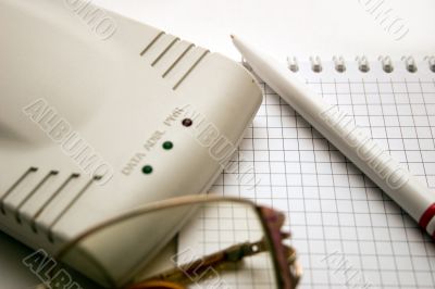 modem, notebook, pen and glasses