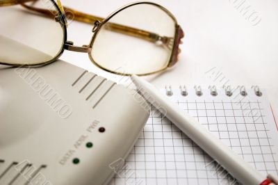 modem, notebook, pen and glasses