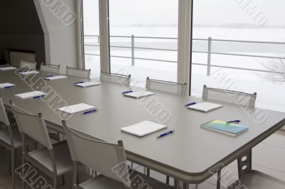 A grey table with grey chairs and notebooks laying