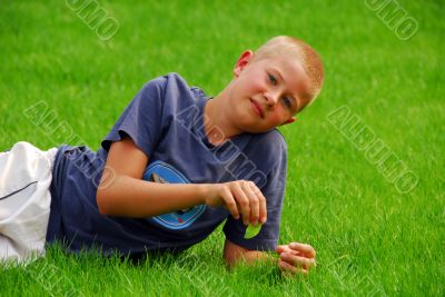 young boy is resting on the grass