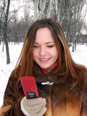 The girl in the winter in park with phone