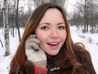 The girl in the winter in park speaks by phone