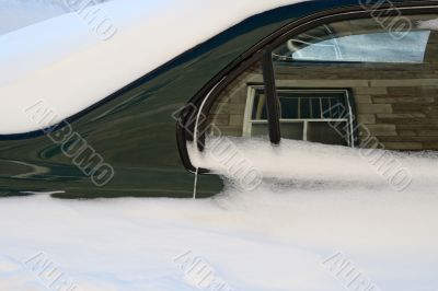 Car in the deep snow reflecting buildings around
