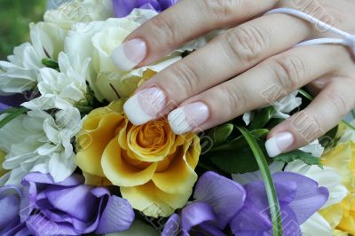 The gentle hand of the bride lays on a bouquet