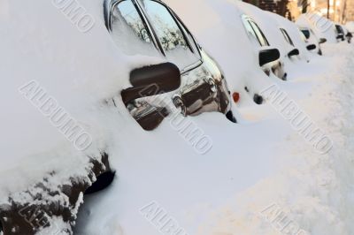 Row of cars covered by deep snow