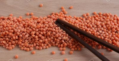 Raw red lentil on a wooden plate with sticks